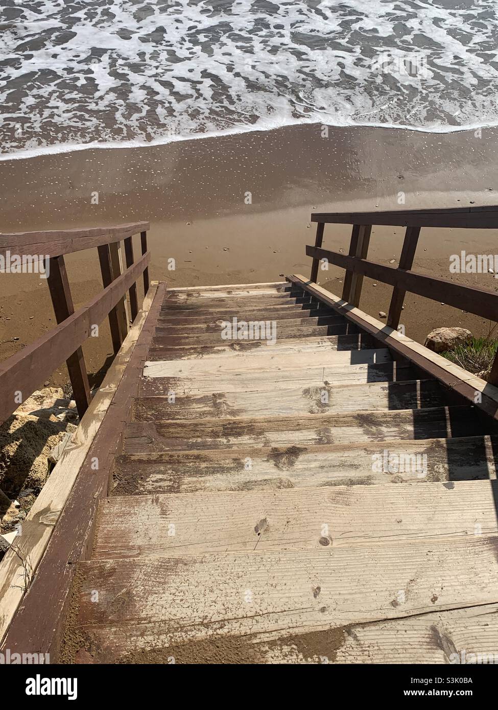 Wooden staircase leading down into the sea at Xi beach - Smartphone Captured Stock Image