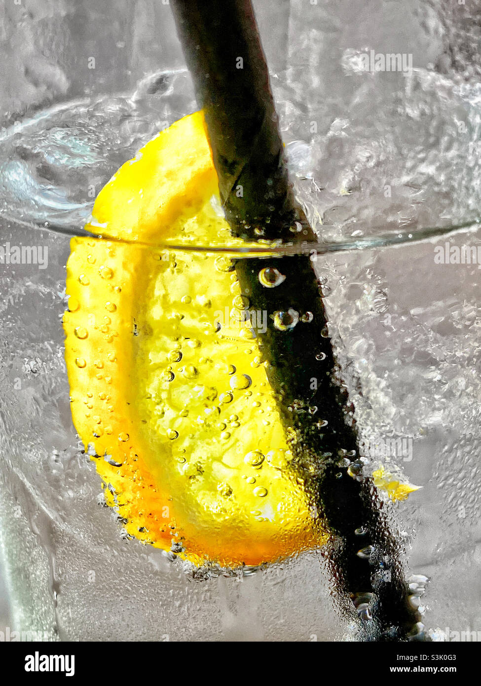 A lemon slice sits between ice cubes in a glass of lemonade drink. Individual bubbles are clearly visible within the drink. Photo ©️ COLIN HOSKINS. - Smartphone Captured Stock Image