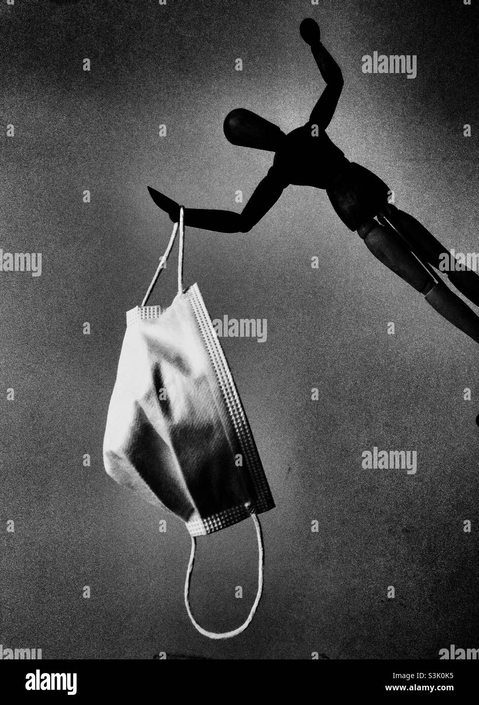 Gloomy image of a wooden doll holding a face mask - Smartphone Captured Stock Image