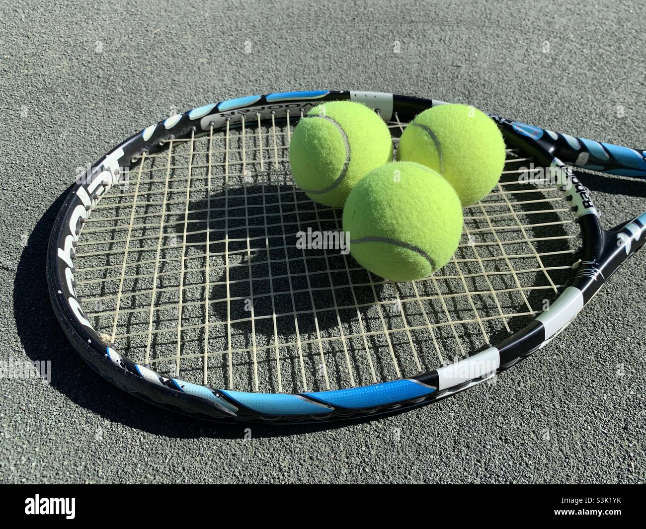 Tennis balls and tennis racket lying in tennis court surface. - Smartphone Captured Stock Image