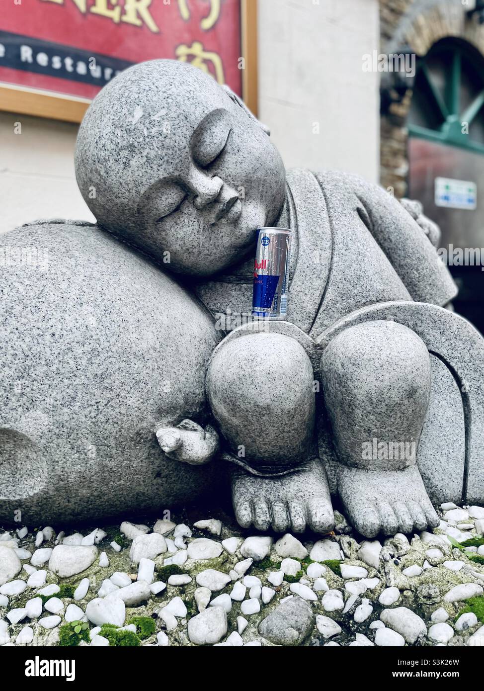 Sleeping statue with a can of red bull in Chinatown Stock Photo