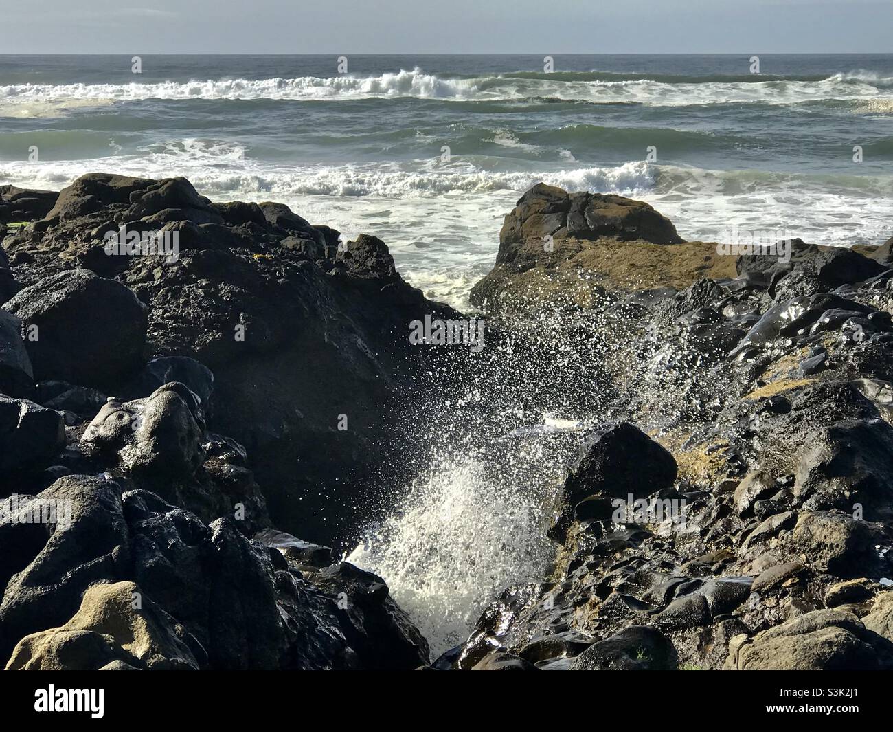 Water spouting from a rocky cave Stock Photo