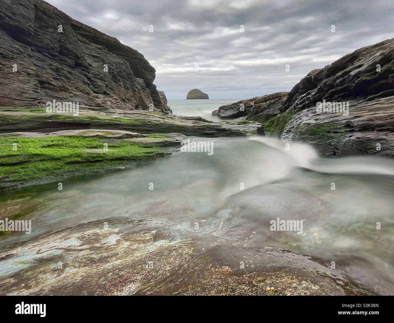 Stream running to the sea at Trebarwith Strand, North Cornwall with Gull Rock in the distance. Stock Photo