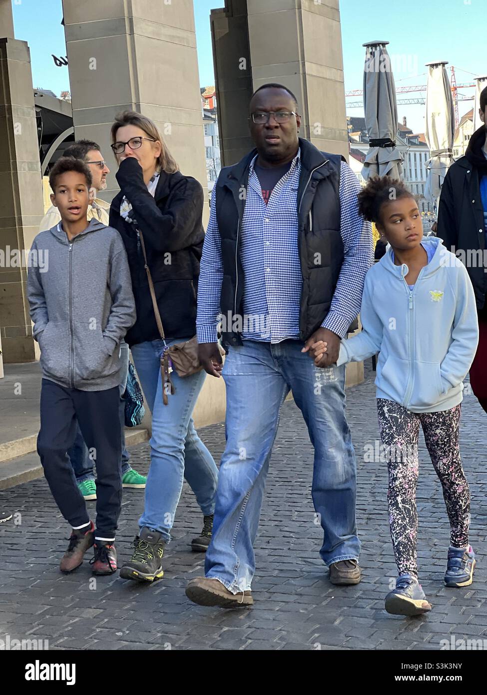 Interracial family two heterosexual parents and two children walking in the streets of old town Zürich in Switzerland. They enjoy their time together. Stock Photo
