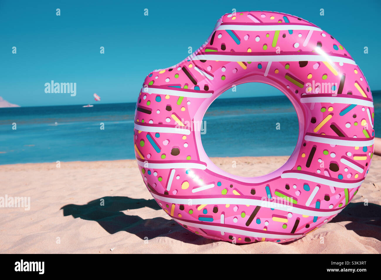 a pink doughnut-like float on sand - Smartphone Captured Stock Image