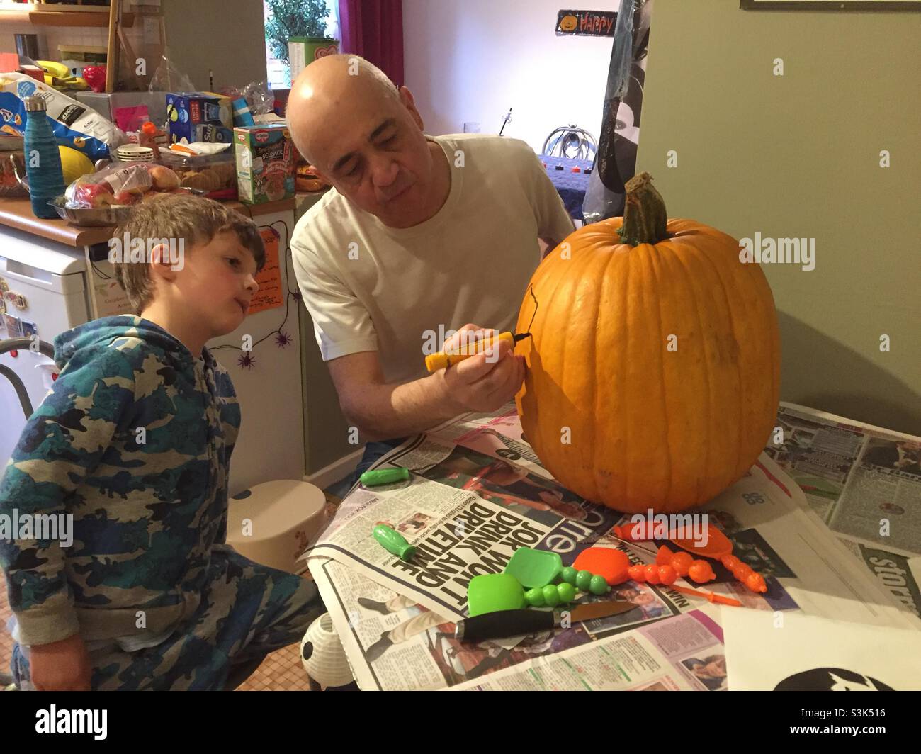 A child and grandfather prepare to carve a large pumpkin Stock Photo