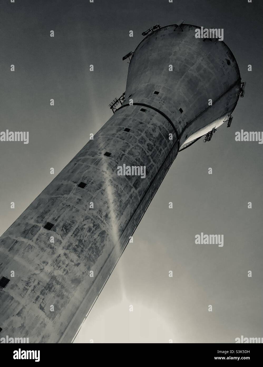 Old water tower used for radio and cell phone masts, against clear sky. Black and White. Les Yvelines, France. - Smartphone Captured Stock Image