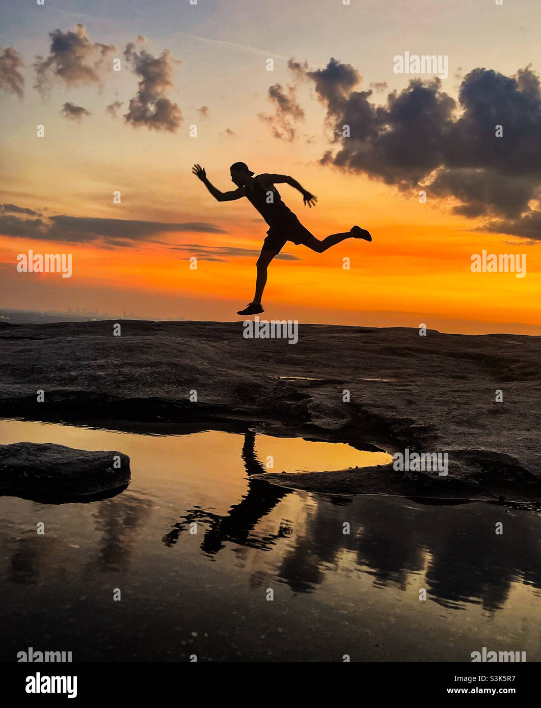 Silhouette of a man jumping in the sunset on top of Stone Mountain Stock Photo