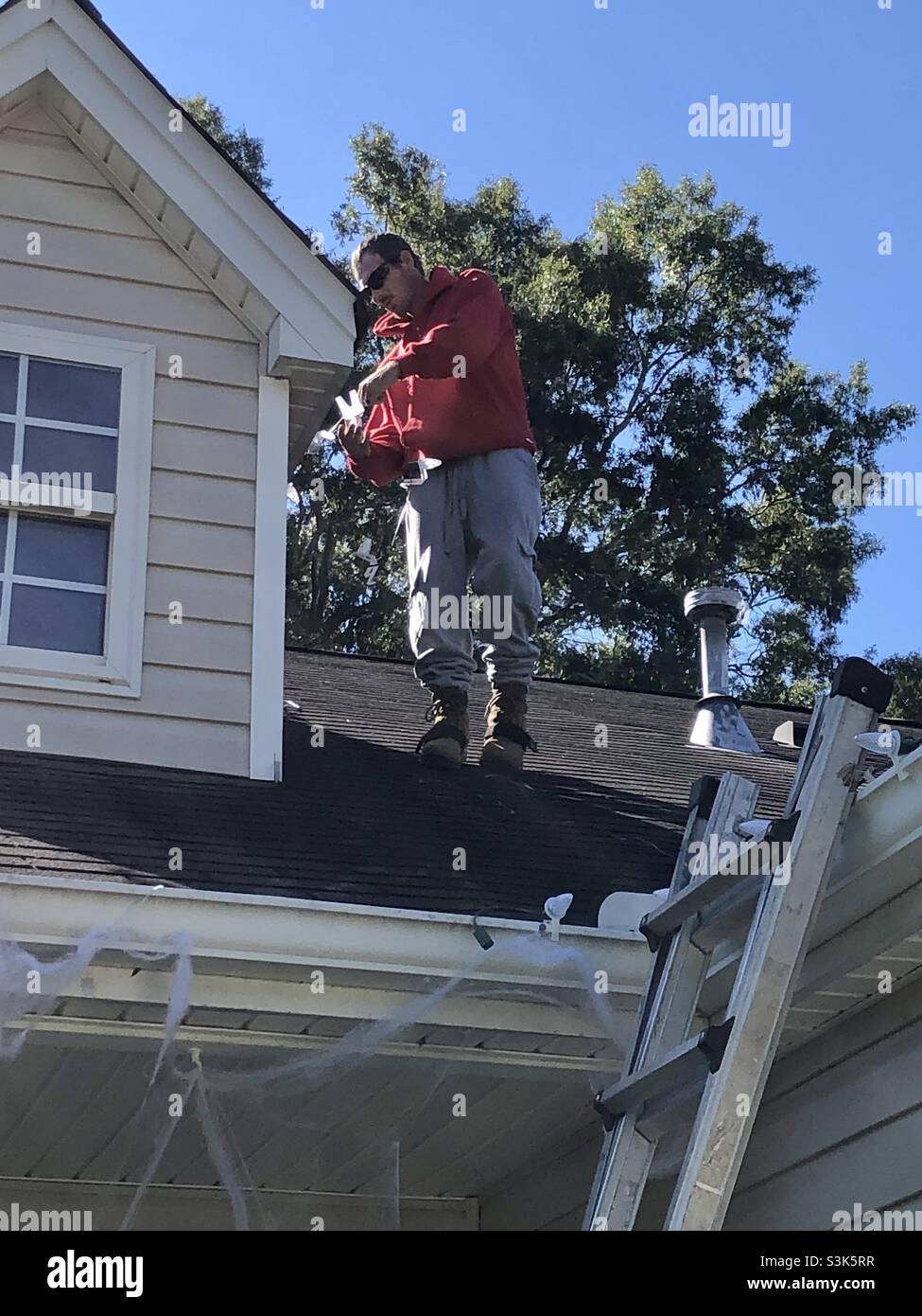 Putting up Christmas lights on roof Stock Photo Alamy