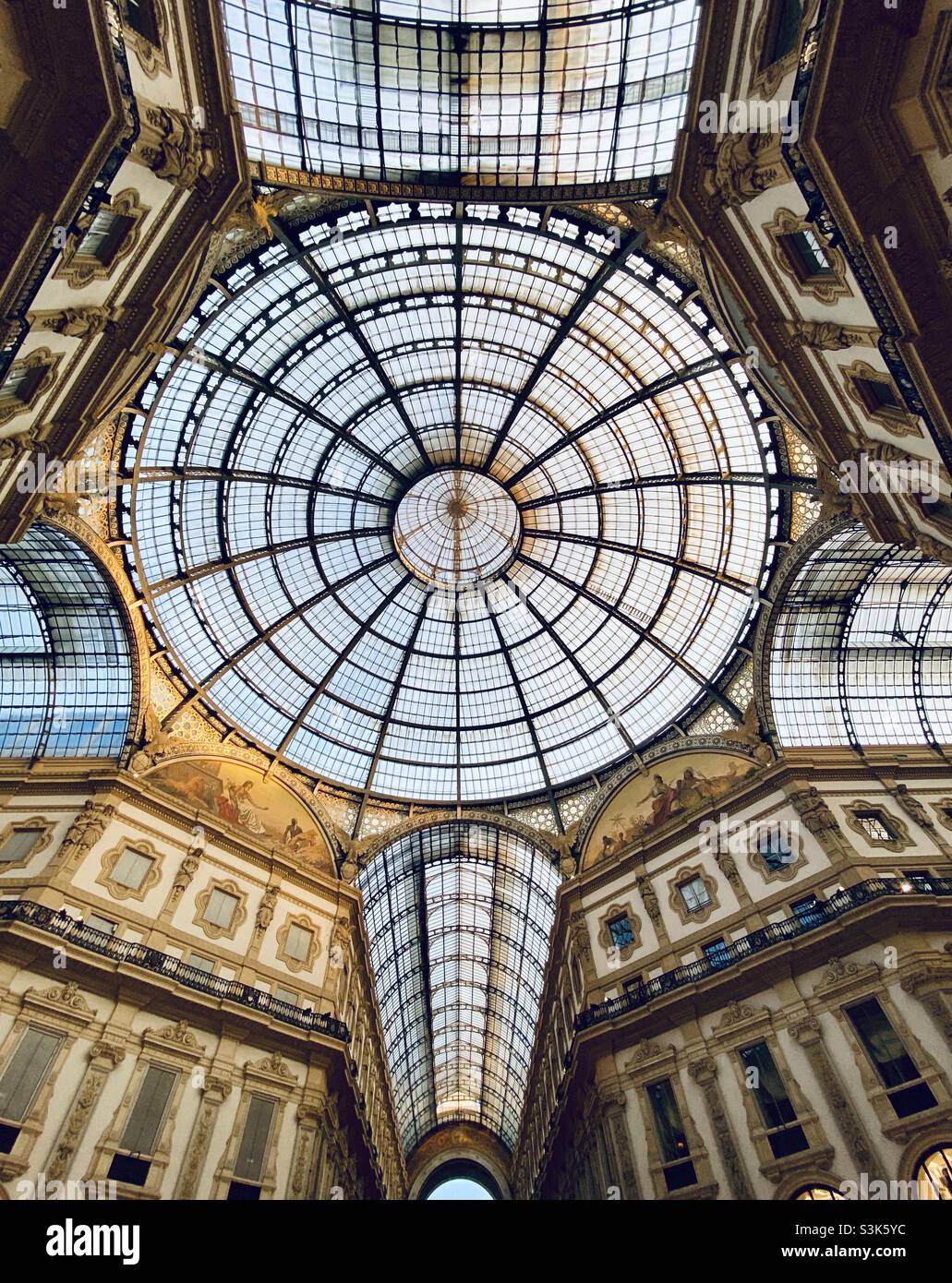 The iconic wrought iron and glass domed ceiling of the Galleria Vittorio Emanuele II, the landmark shopping arcade in Milan built in 19th century abutting the Piazza del Duomo - Smartphone Captured Stock Image