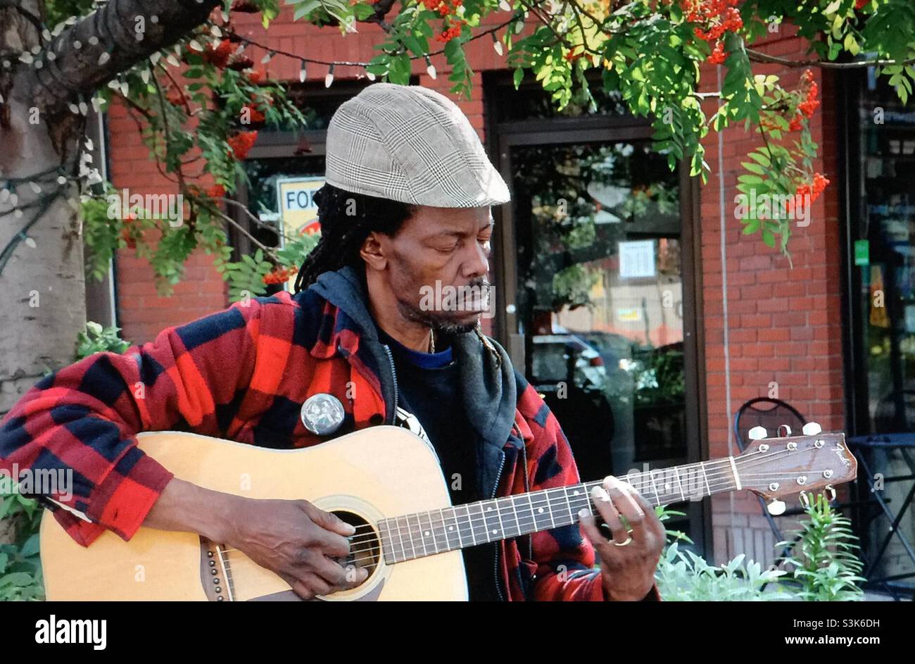 Street photography, Kensington in Calgary, Alberta , entertainer, busker, musician, guitar played, singer - Smartphone Captured Stock Image