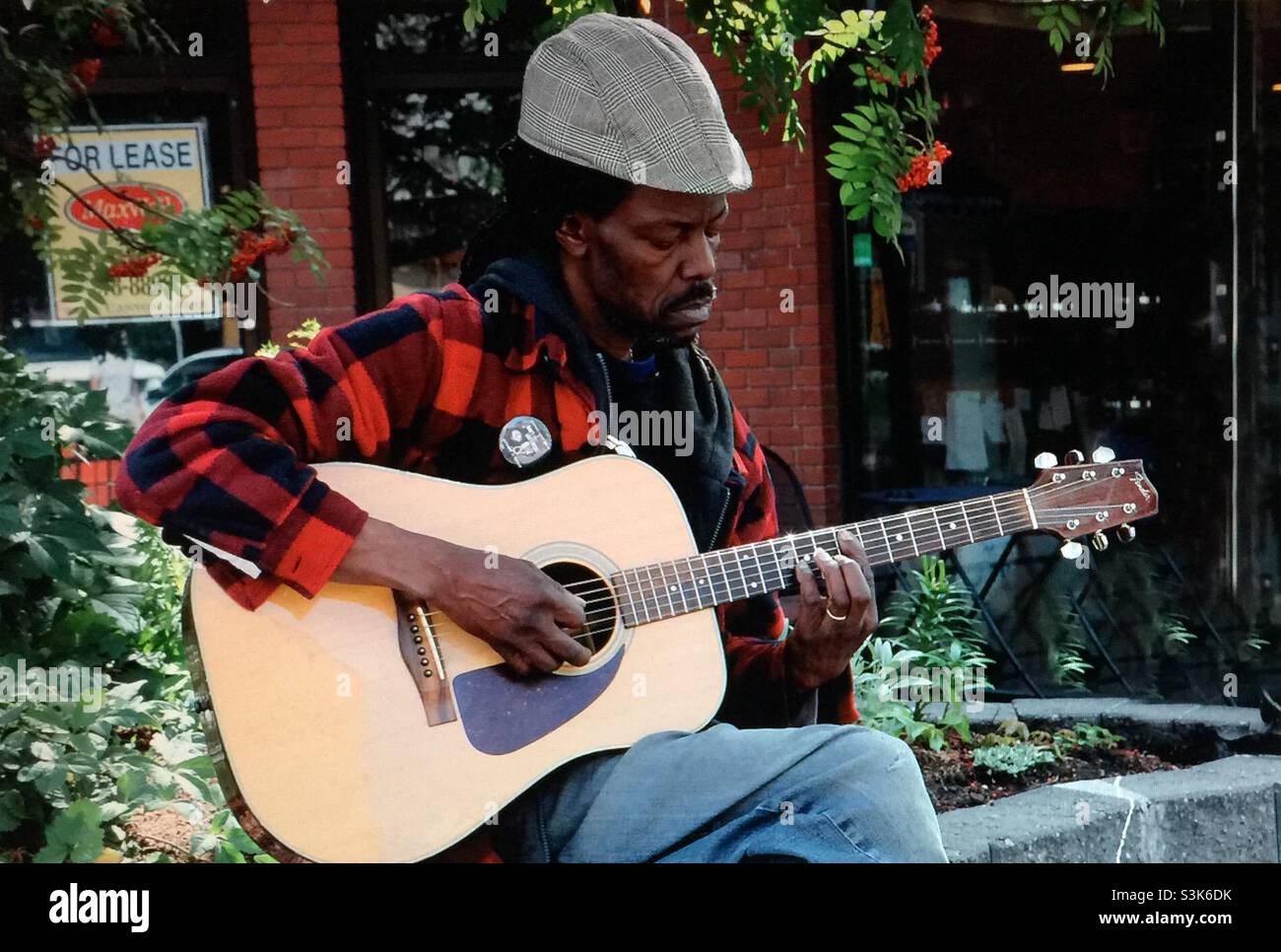 Street photography, Kensington in Calgary, Alberta , entertainer, busker, musician, guitar player, singer - Smartphone Captured Stock Image