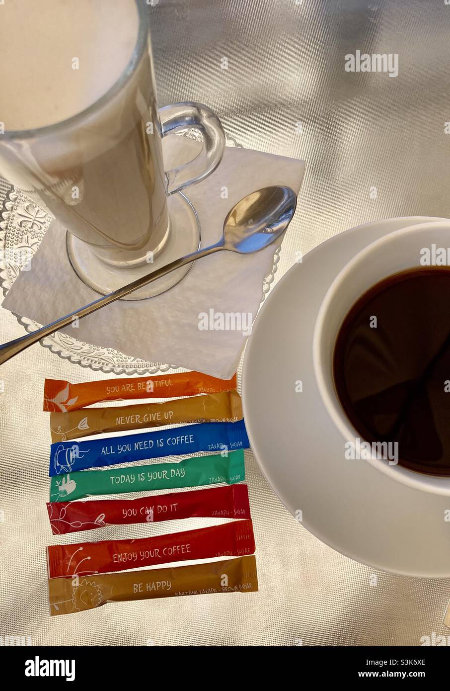 Time for Coffee. A tall latte and short Americano with sugar sachets showing inspirational quotes. Stock Photo