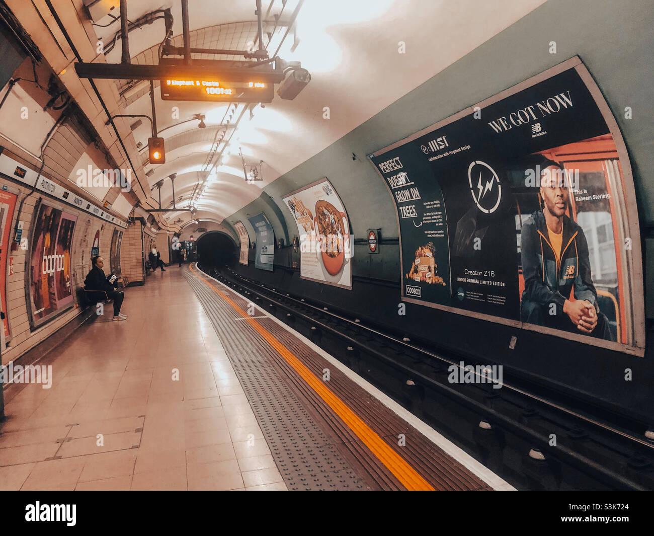 A handful of passengers wait on the platform for a train at Paddington London Underground Station. - Smartphone Captured Stock Image