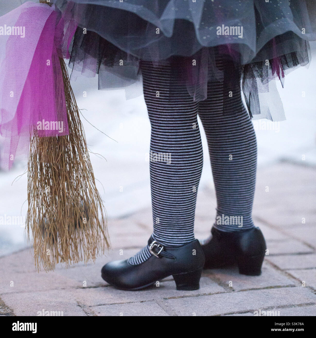 Young witch legs with her broom. Halloween costume Stock Photo
