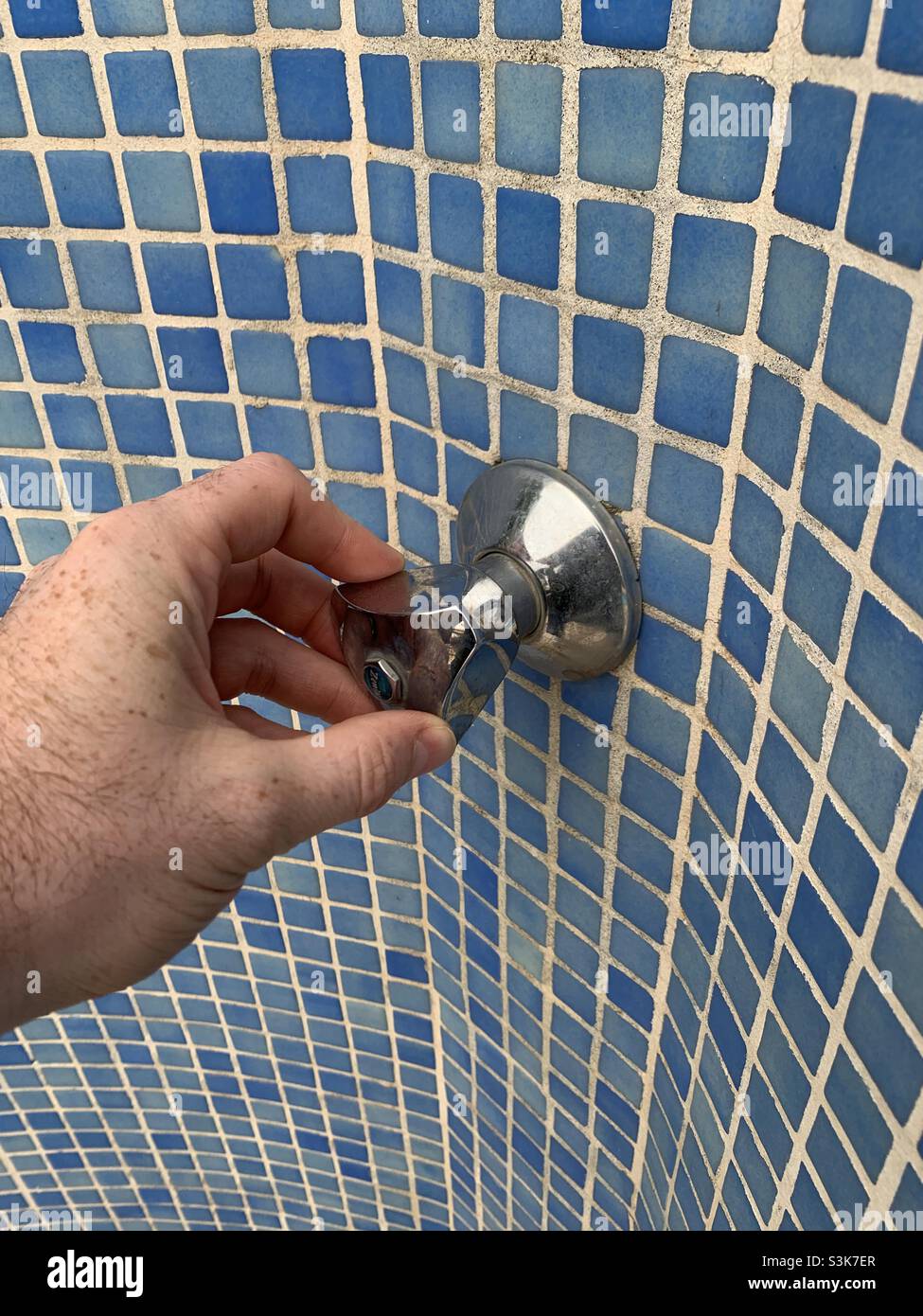 Turning on an outdoor shower.  Beach holiday - Smartphone Captured Stock Image