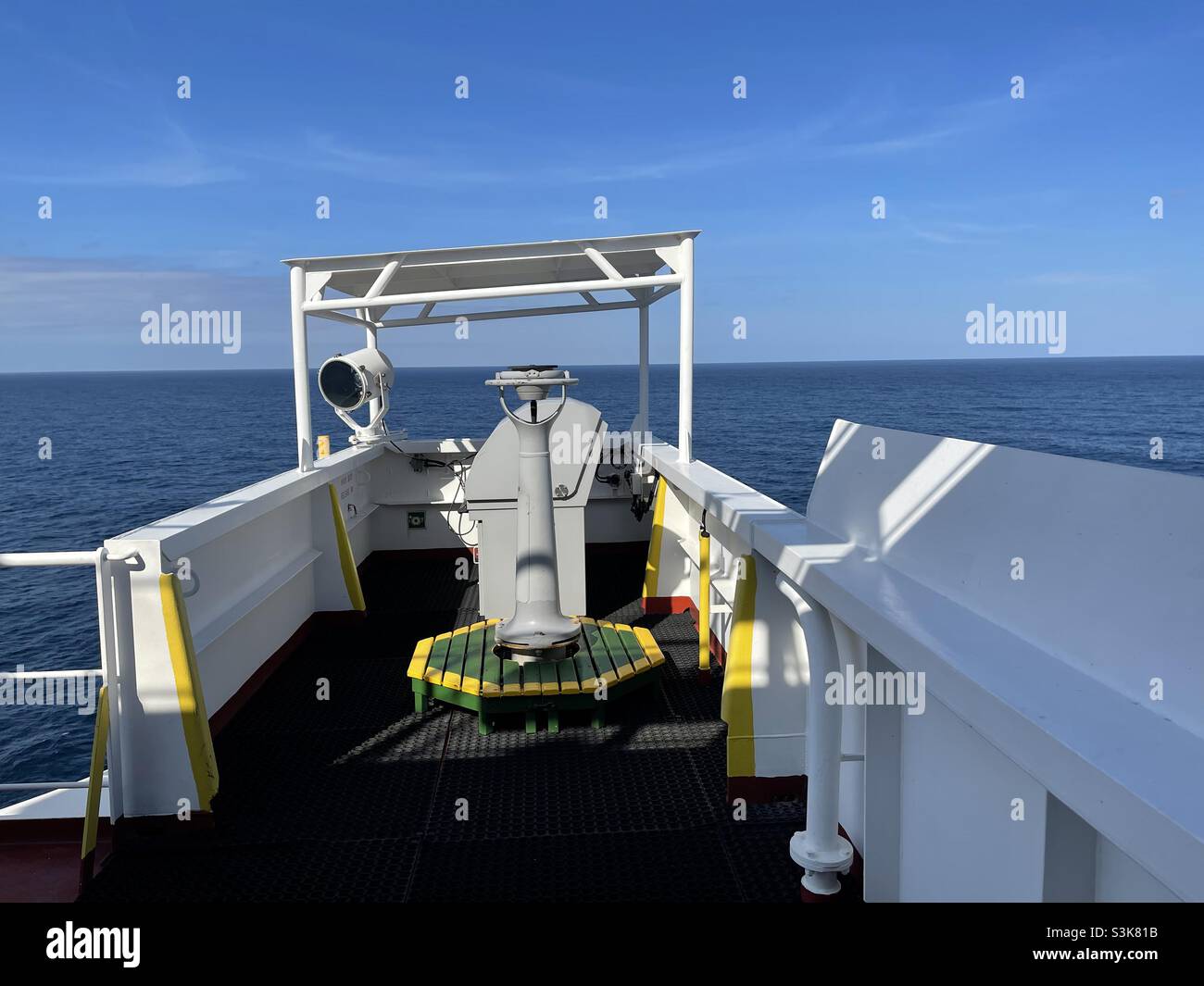 Wing of navigational bridge of the merchant container vessel with gyro compass repeater, Panama shelter, search light and remote control column for steering, bow thrusters and engine telegraph. Stock Photo