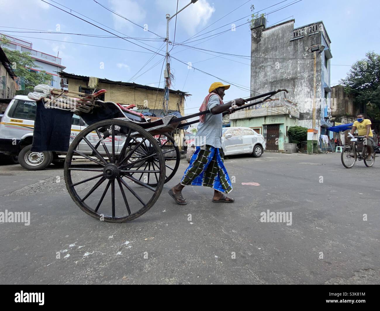 A Rickshaw puller manually driving the rickshaw in the street of Kolkata - Smartphone Captured Stock Image