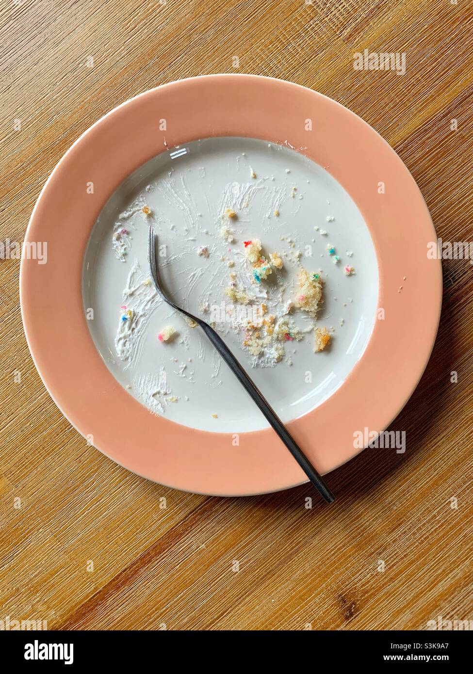 Plate with remains of birthday cake, crumbs and icing, and fork - Smartphone Captured Stock Image