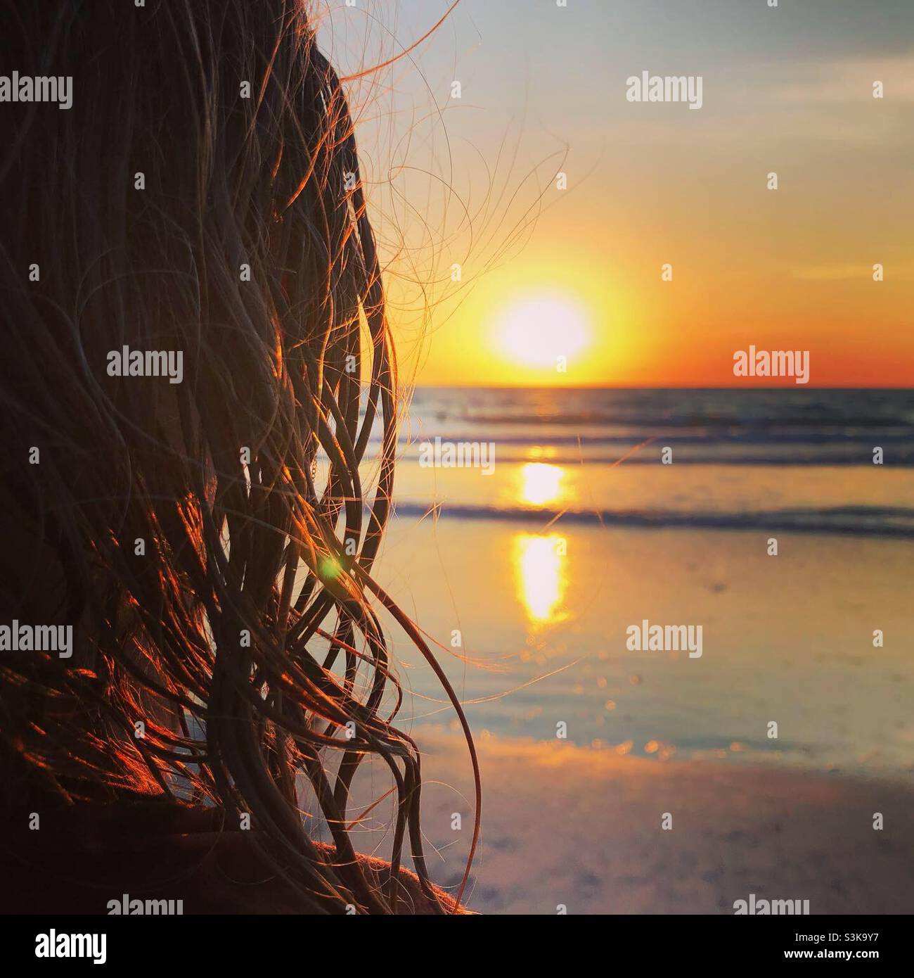 A woman wit wet hair enjoys the sunset on Cable Beach in Broome WA - Smartphone Captured Stock Image