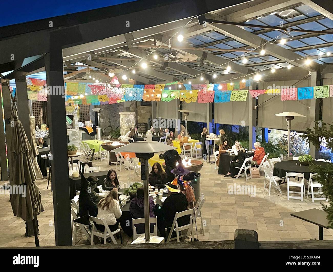 People dining in a covered patio area of a restaurant during “WitchFest”, an annual Fall Festival held each October at Gardner Village in the Salt Lake valley, Utah, USA. - Smartphone Captured Stock Image