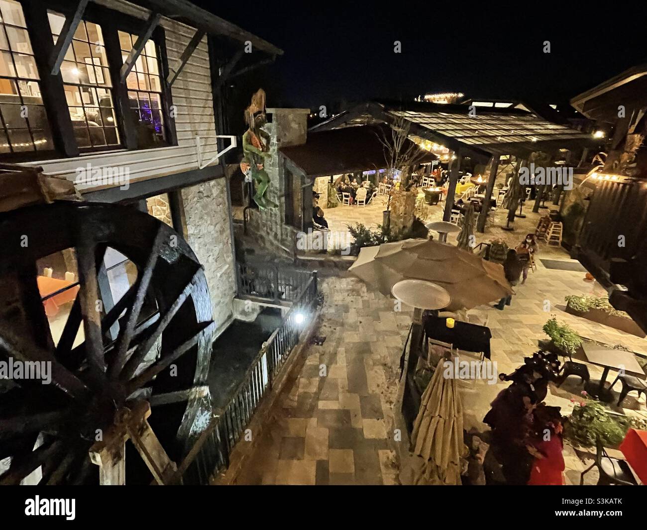 A semi-aerial view looking down over the plaza and patio area of the restaurant at Gardner Village, Utah, USA during its’ annual “WitchFest”. A working antique waterwheel can be seen on the left. - Smartphone Captured Stock Image