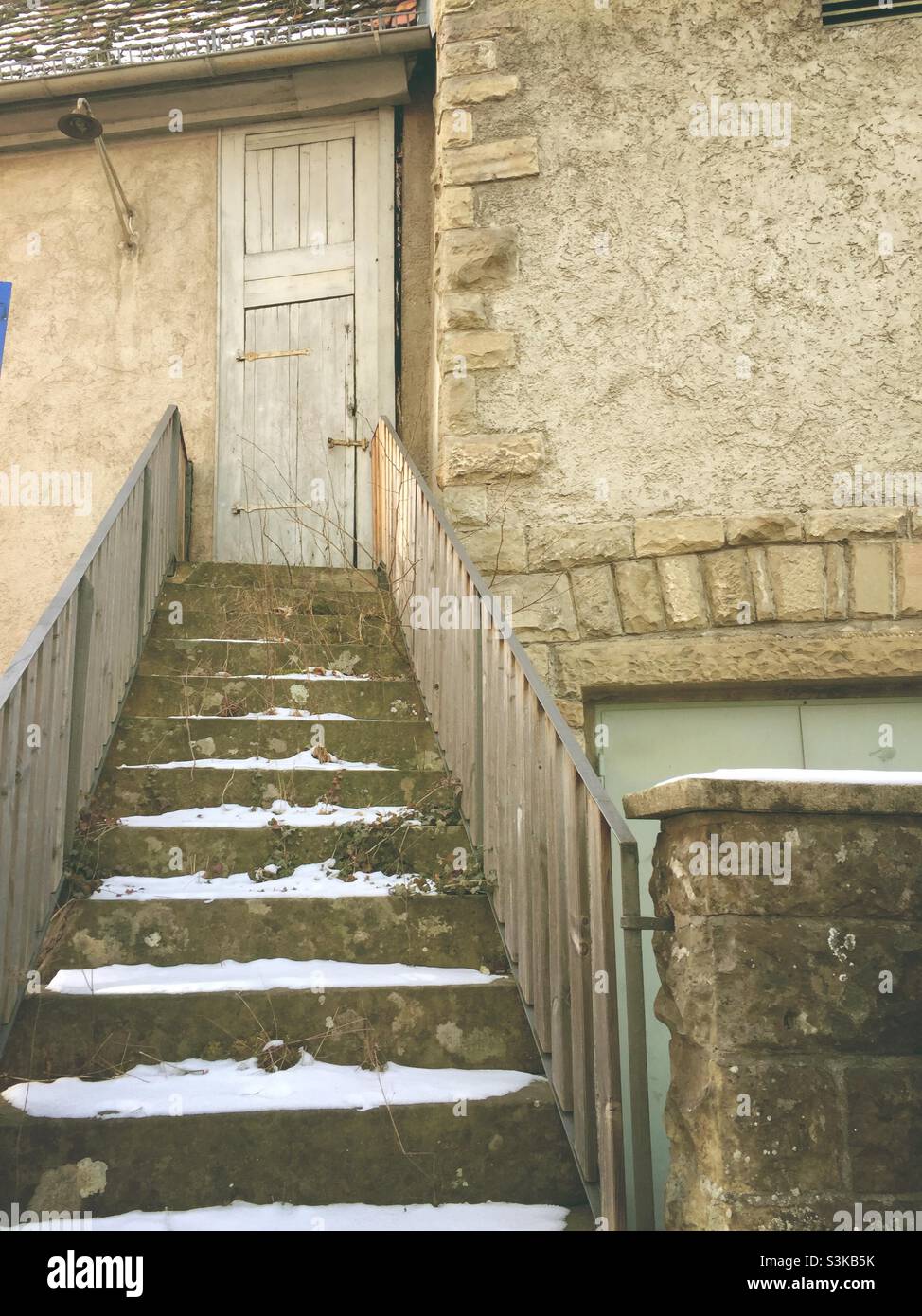 Old snow covered stone stairs leading to a closed wooden door - Smartphone Captured Stock Image