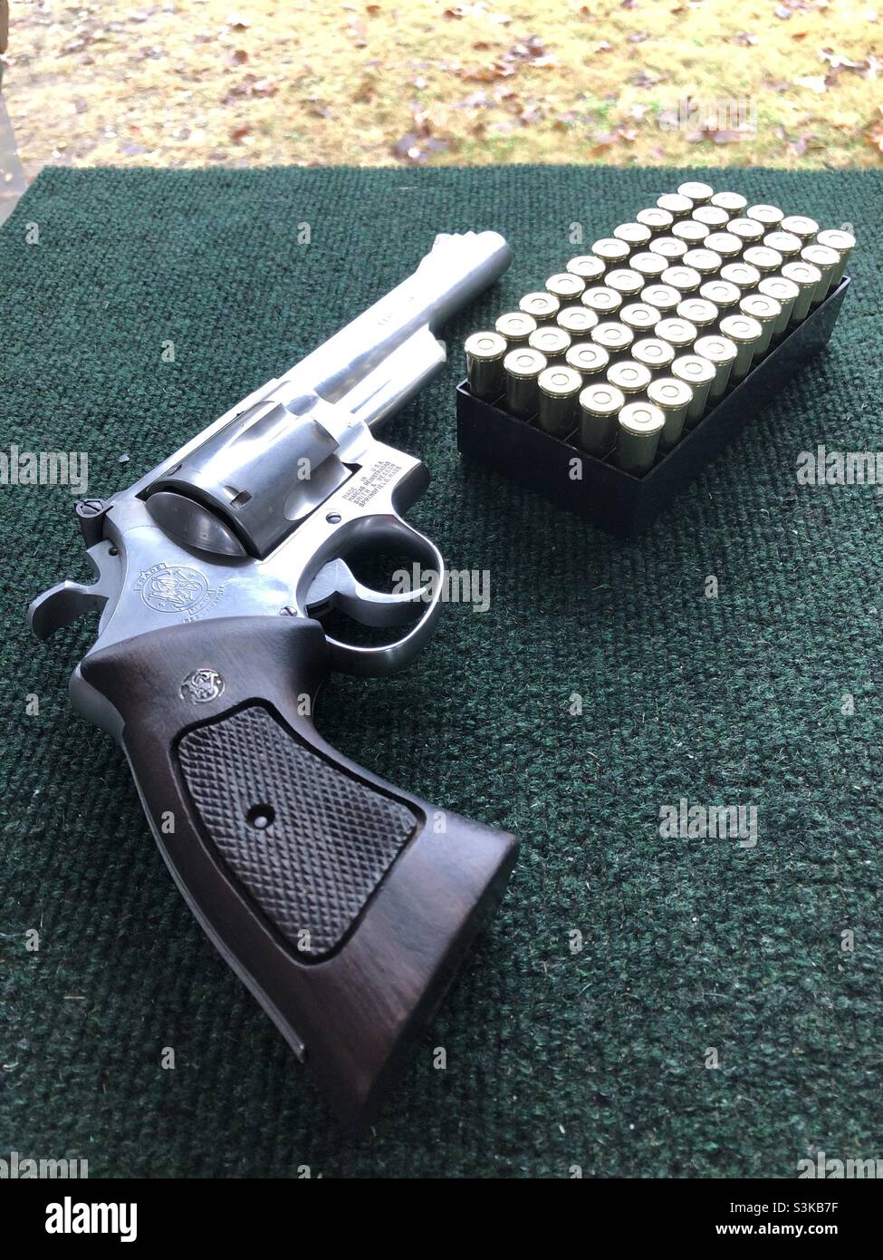 A Magnum 44 handgun with a pack of bullets and n a table at a shooting range in Texas USA - Smartphone Captured Stock Image