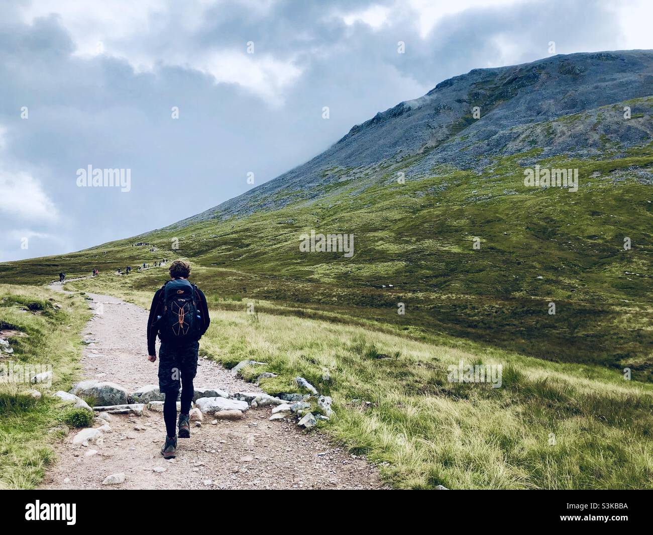 A man walks on a path near the Ben Nevis mountain range in Scotland in the UK - Smartphone Captured Stock Image