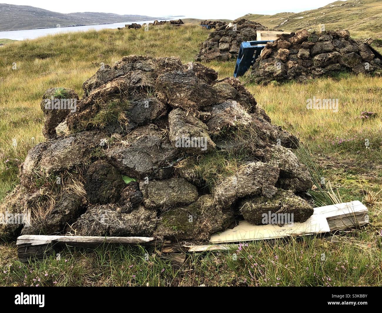 A large pile of peat heaped up and ready for collection on the Outer Hebrides in Scotland in the UK Stock Photo