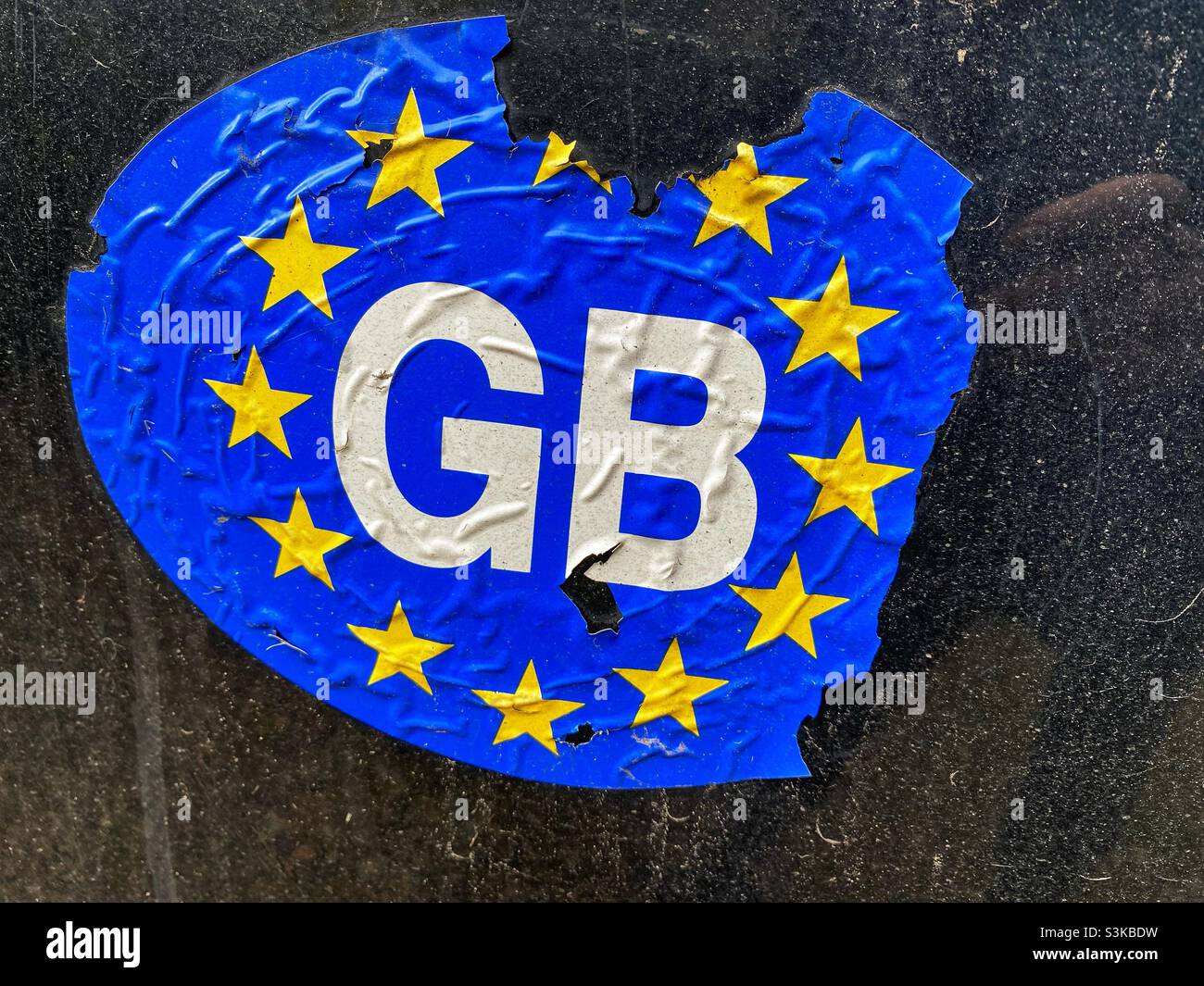 A worn GB car sticker on the back of a car. The Great Britain (GB) sticker is no longer valid and has been replace by one which says ‘UK’ Stock Photo