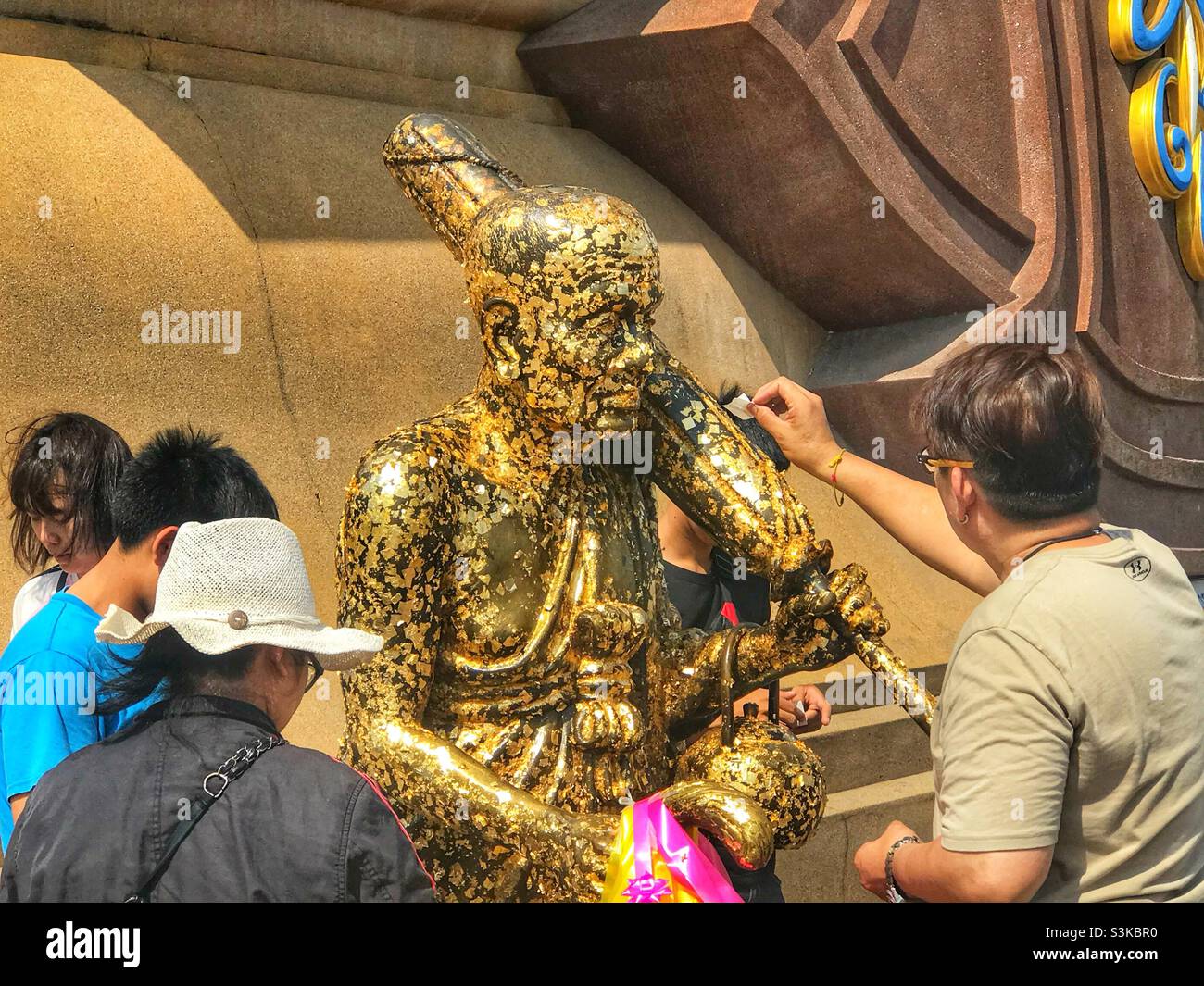Devotees place gold leaf on a statue of Luang Phor Thuad  at Wat Huay Mongkol in Hua Hin, Thailand - Smartphone Captured Stock Image