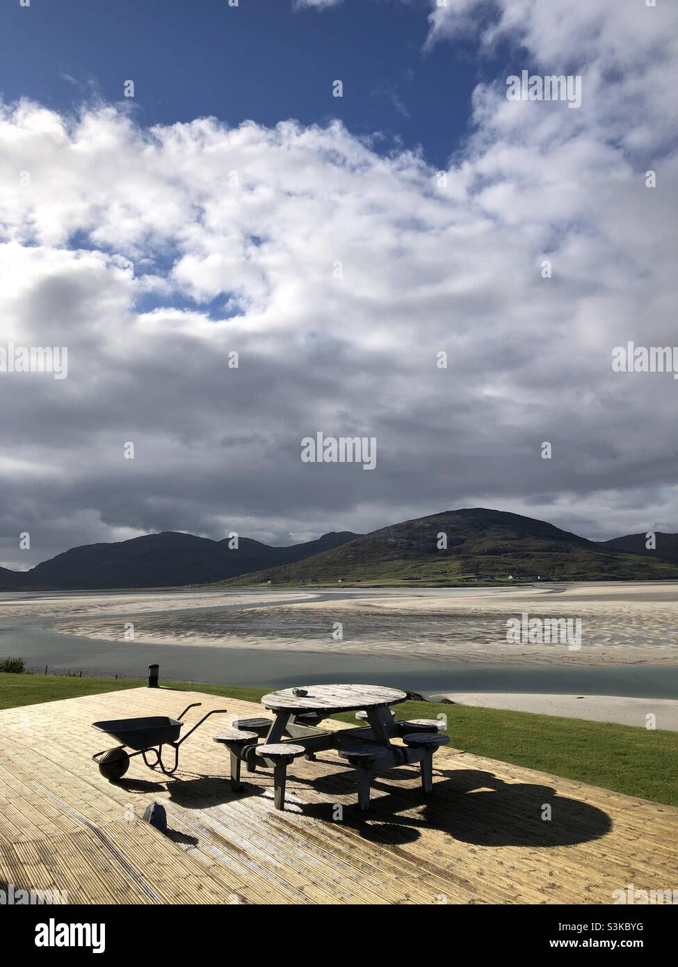 The deck in front of a house with outside seating and a wheelbarrow overlooking Luskentyre beach in the Outer Hebrides in Scotland - Smartphone Captured Stock Image