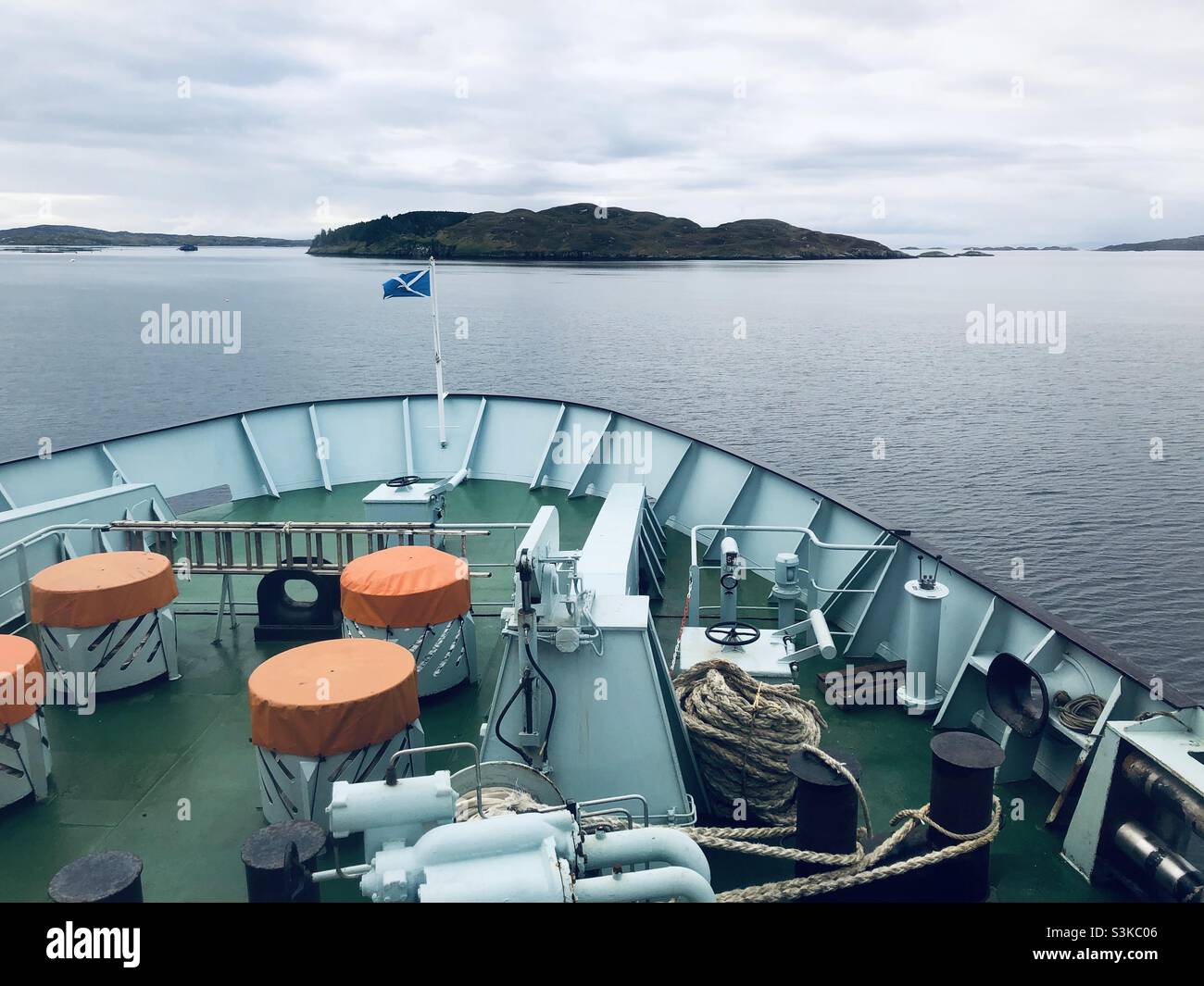 The bow of a ship with the Scottish flag flying in the wind with a small island ahead - Smartphone Captured Stock Image The bow of a ship with the Scottish flag flying in the wind with a small island ahead - Smartphone Captured Stock Image