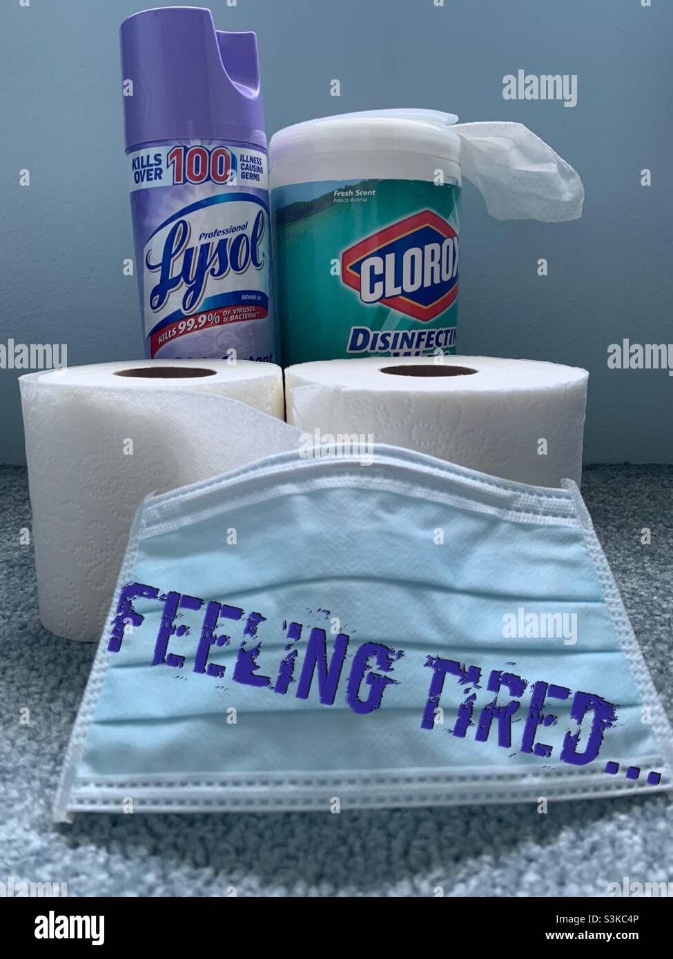 A topical still life of pandemic related items such as cleaning products, toilet paper and a mask, with a caption we can all relate to: Feeling Tired… - Smartphone Captured Stock Image
