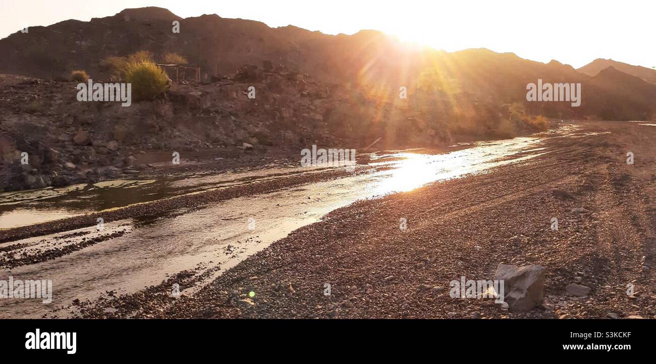 Landscape: orange valley with water running and sunset colors falling on the surrounding hills and land - Smartphone Captured Stock Image