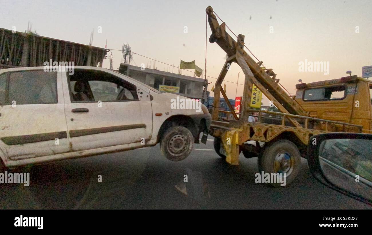 A scrap car is carrying by a vehicle in highway - Smartphone Captured Stock Image