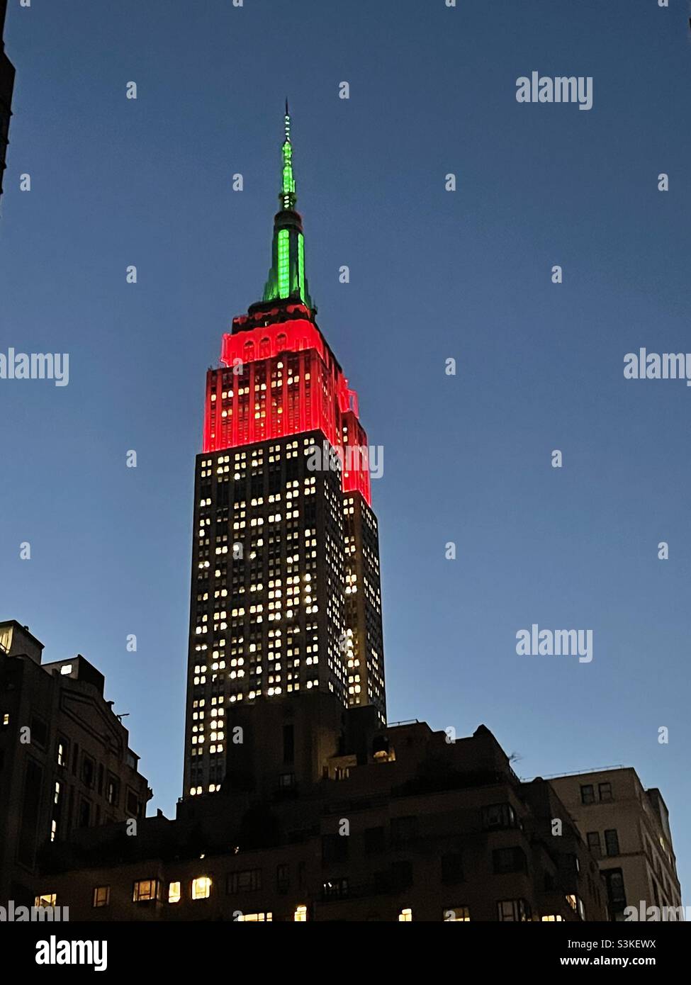 Red & green Tower Lights In Honor of the Opening Night of the 2021 Christmas Spectacular Starring the Radio City Rockettes, Empire State building, New York City - Smartphone Captured Stock Image