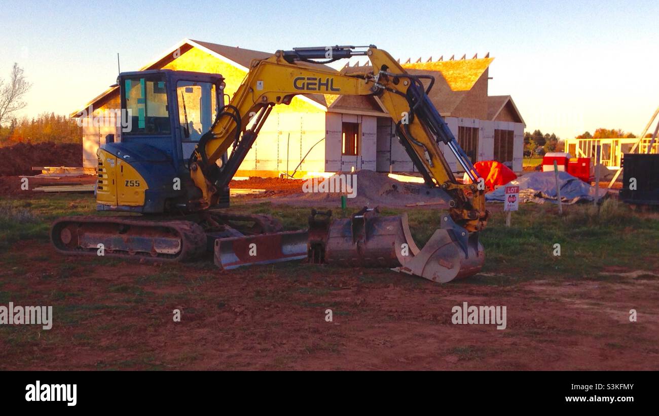 A house construction site with unfinished house and backhoe machinery Stock Photo
