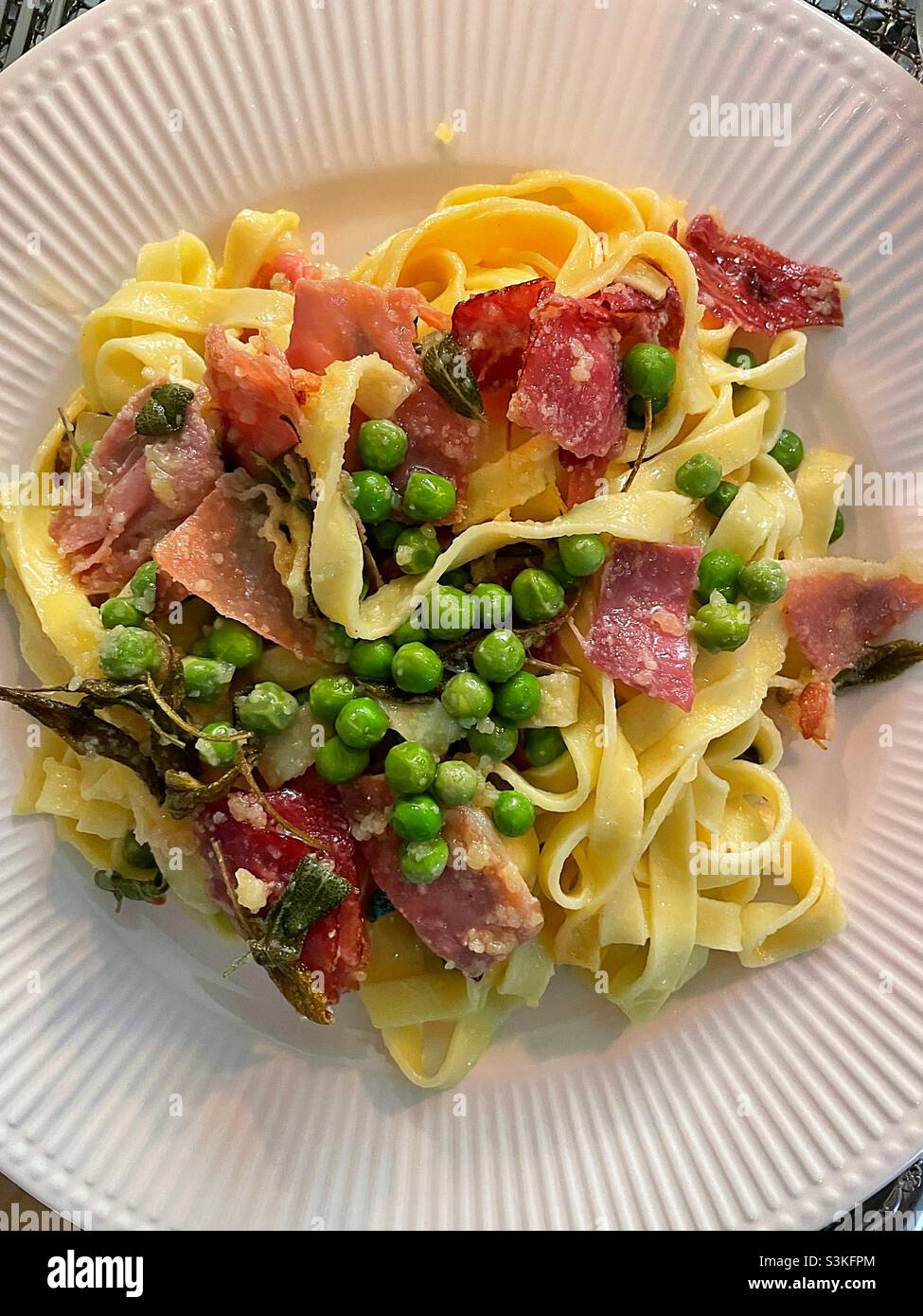 Flat lay of a gourmet pasta dish of fresh fettuccine, English peas and braised prosciutto - Smartphone Captured Stock Image