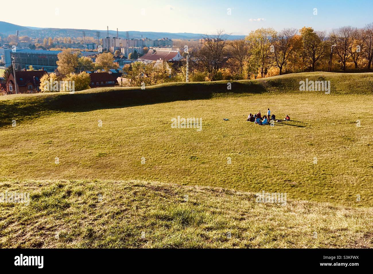 Teenagers sitting and playing in the middle of the grass in ancient amphitheatre, Sopron, Hungary - Smartphone Captured Stock Image