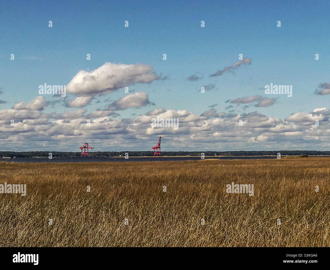 Red structures in background of photo taken from Fort Fisher, North Carolina in November. Unclear whether they are loading cranes or partial structure of some kind. - Smartphone Captured Stock Image