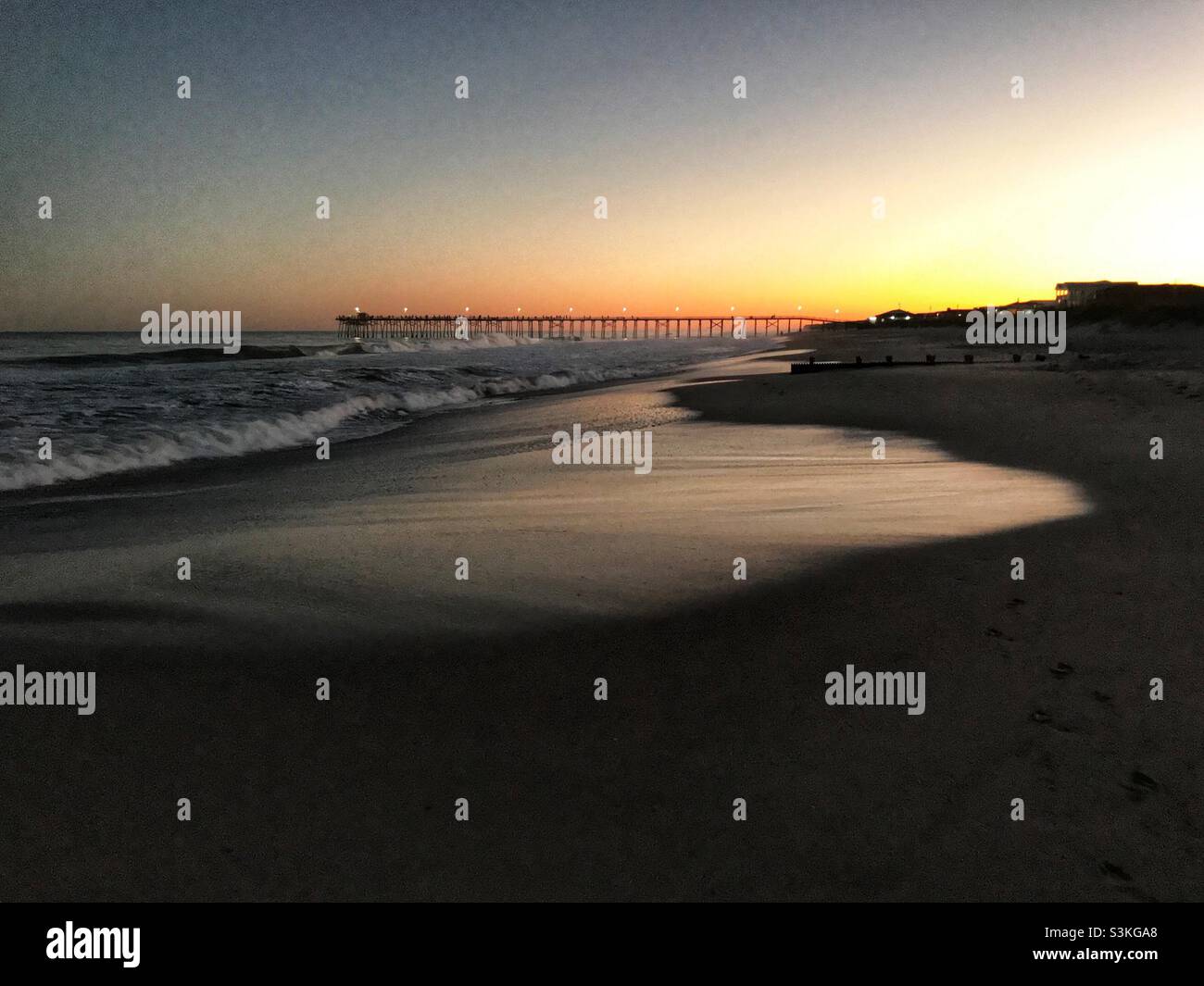 Distant fishing pier down the beach at sunset - Smartphone Captured Stock Image
