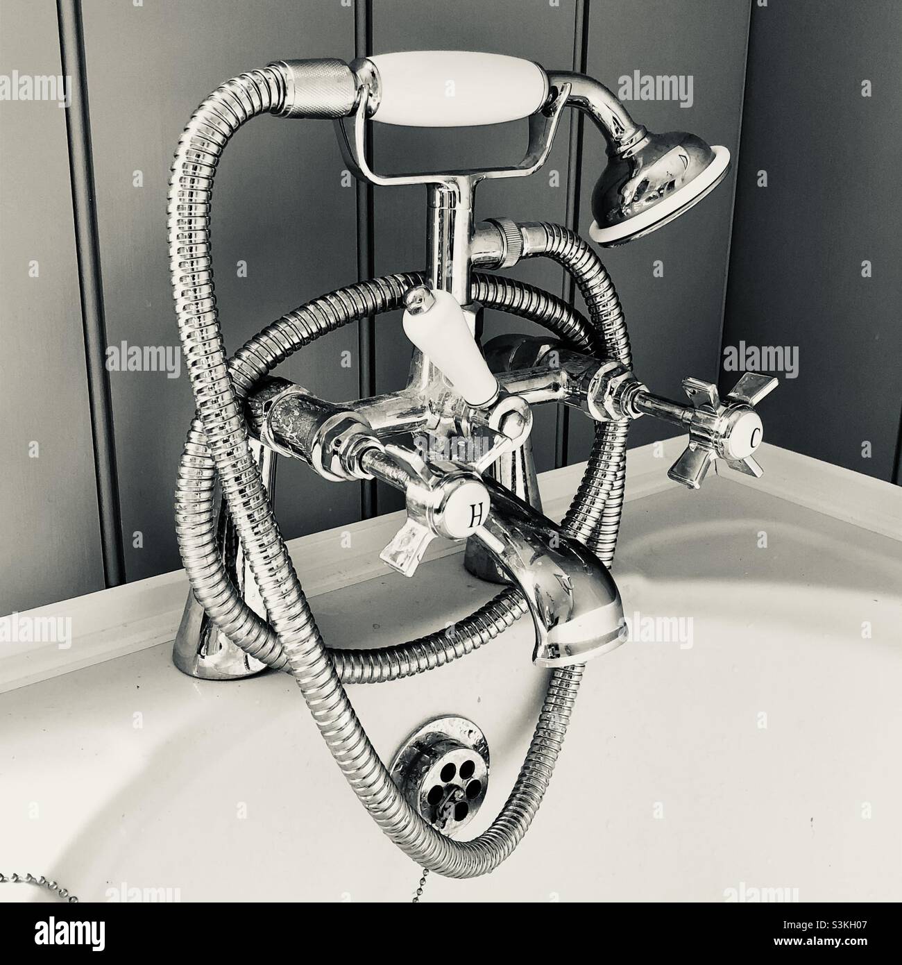 Vintage style bath taps and shower with wall panelling behind Stock