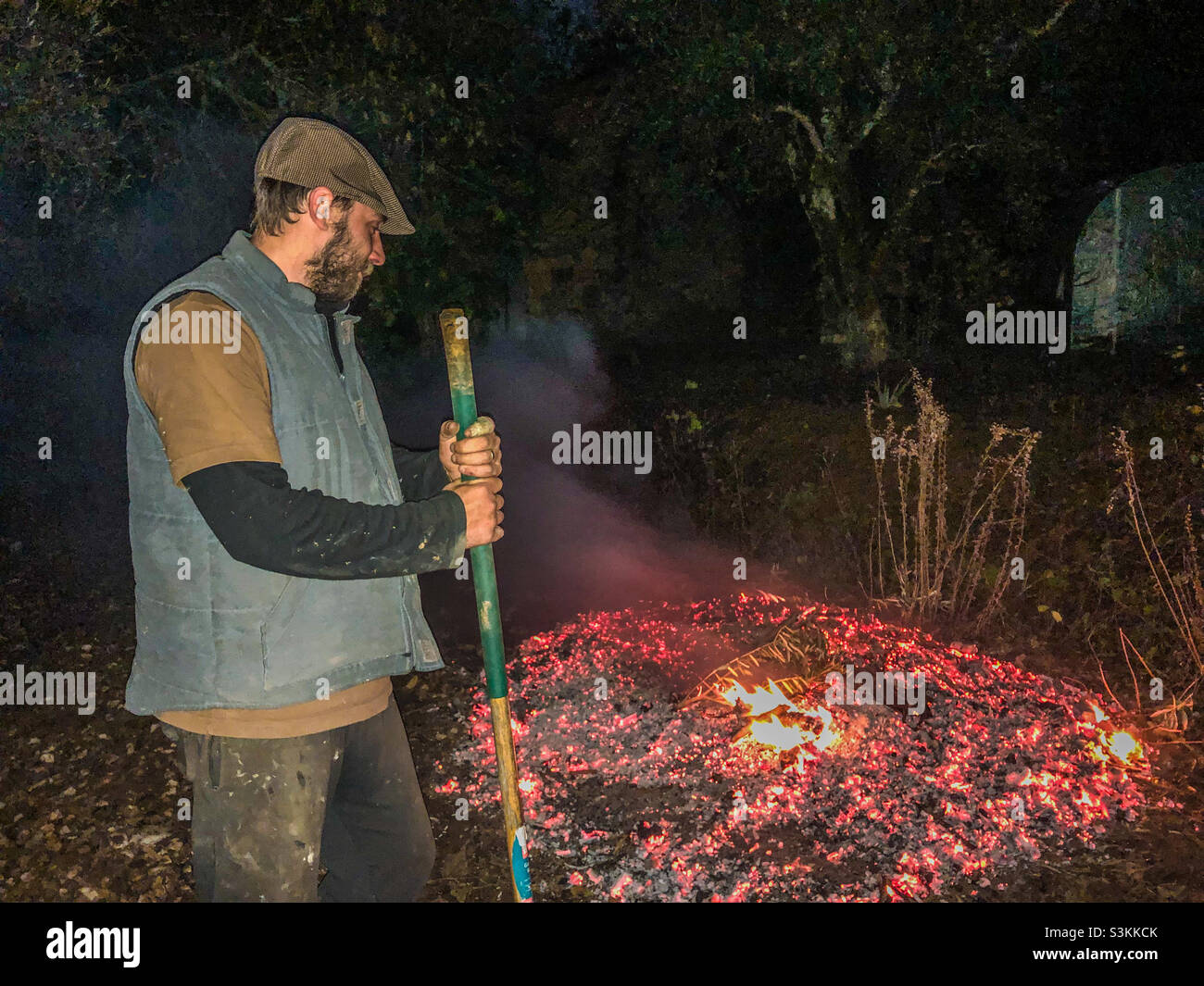 A man attends a garden bonfire, in the dark - Smartphone Captured Stock Image