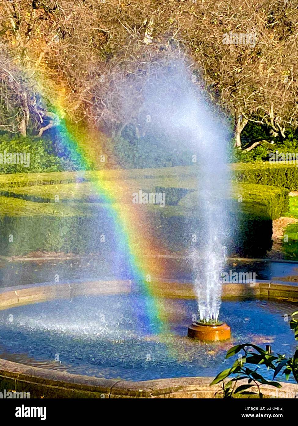 A rainbow appears in the water spray from the Burnett fountain in the conservatory garden of Central Park New York City - Smartphone Captured Stock Image