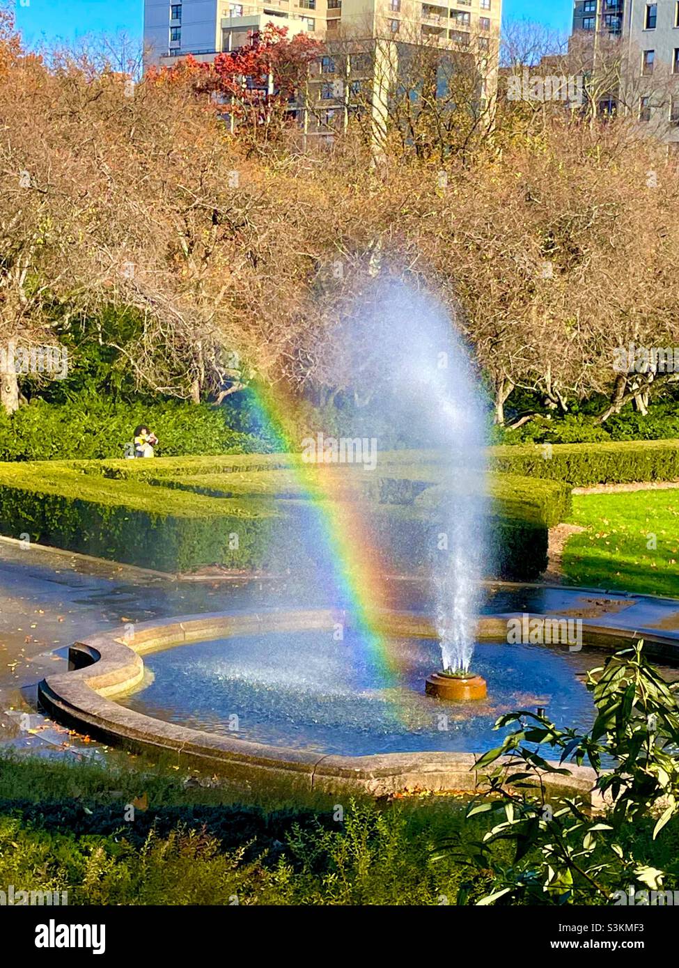 A rainbow appears in the water spray from the Burnett fountain in the conservatory garden of Central Park in New York City - Smartphone Captured Stock Image