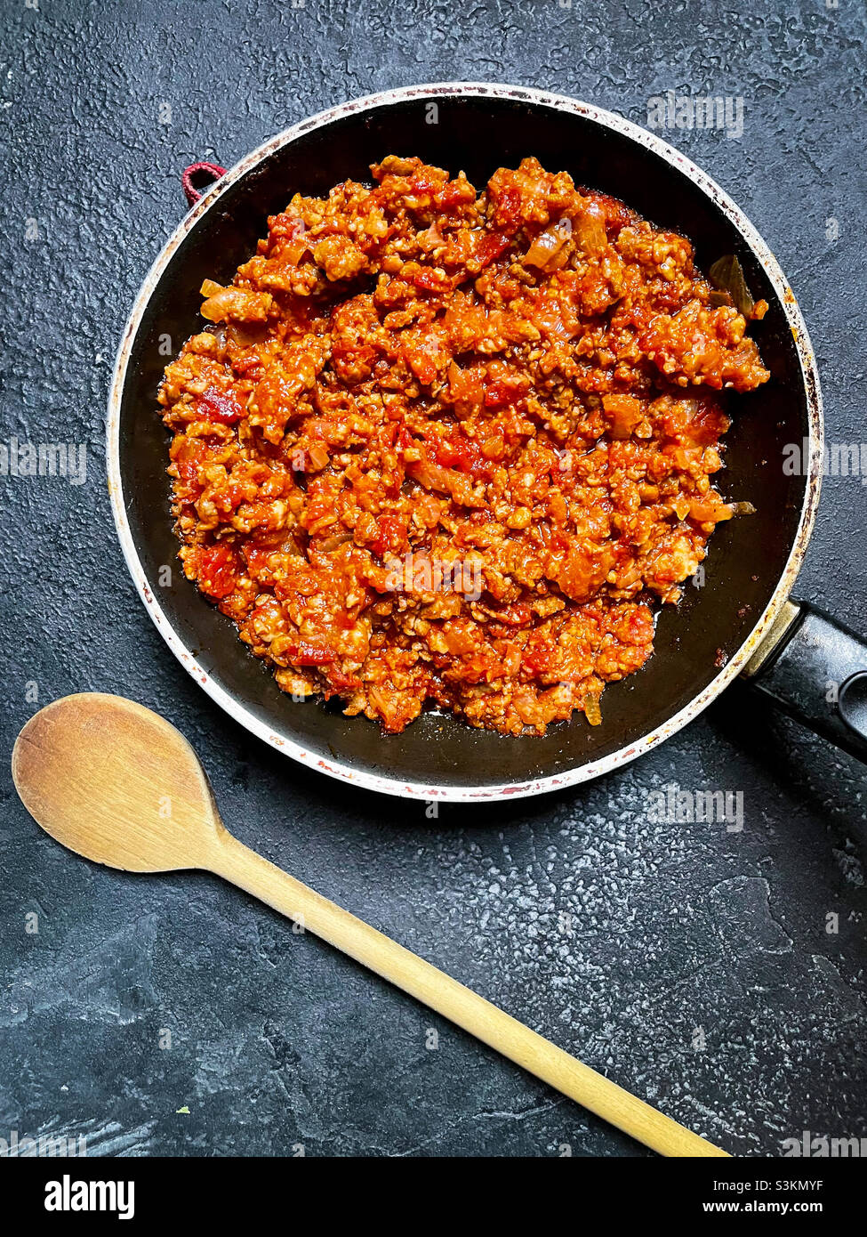 Frying pan with homemade tomato sausage ragout on a black background