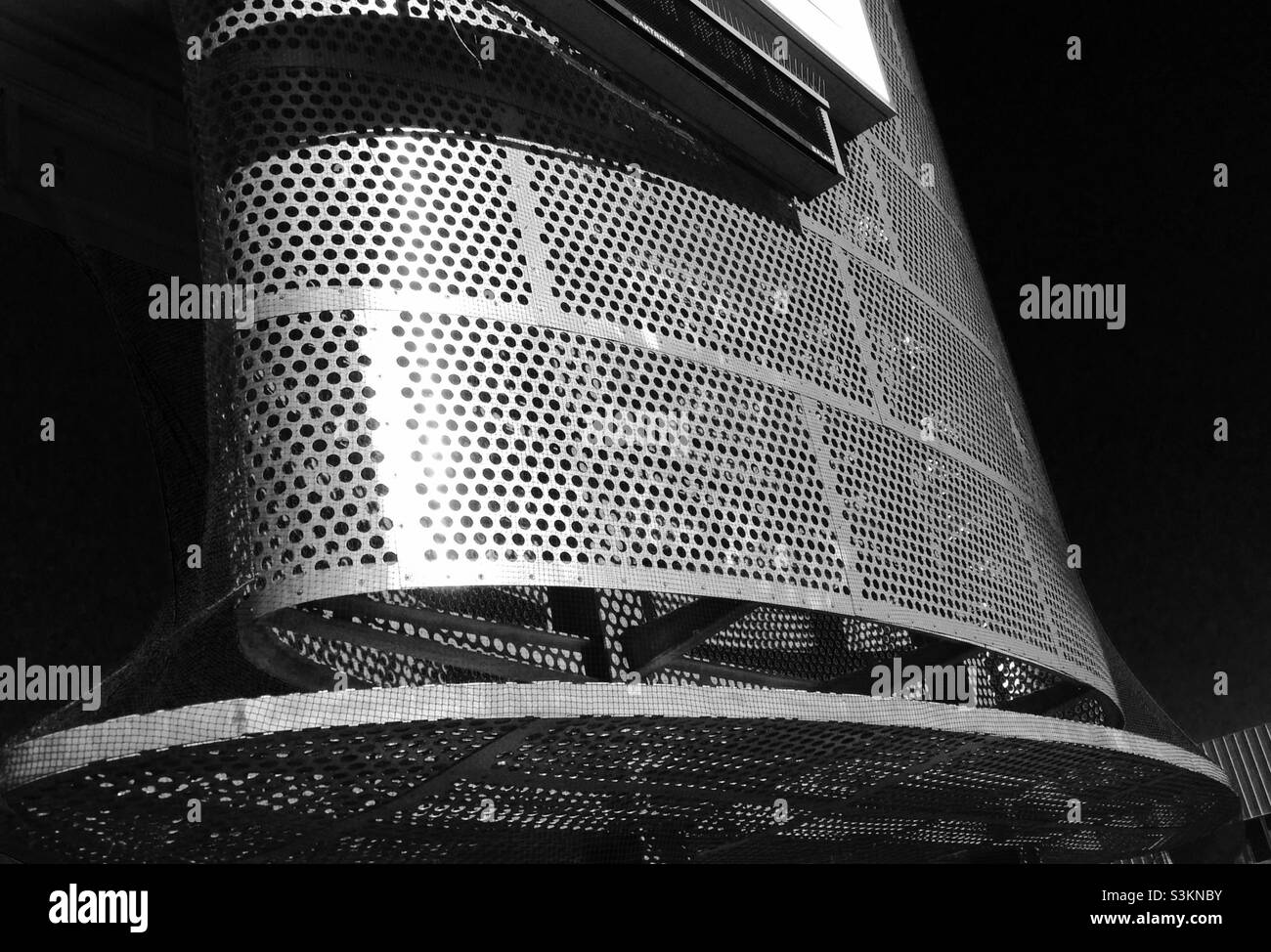 Perforated steel portion of a commercial sign is curved resembles a sculpture, a design element Stock Photo