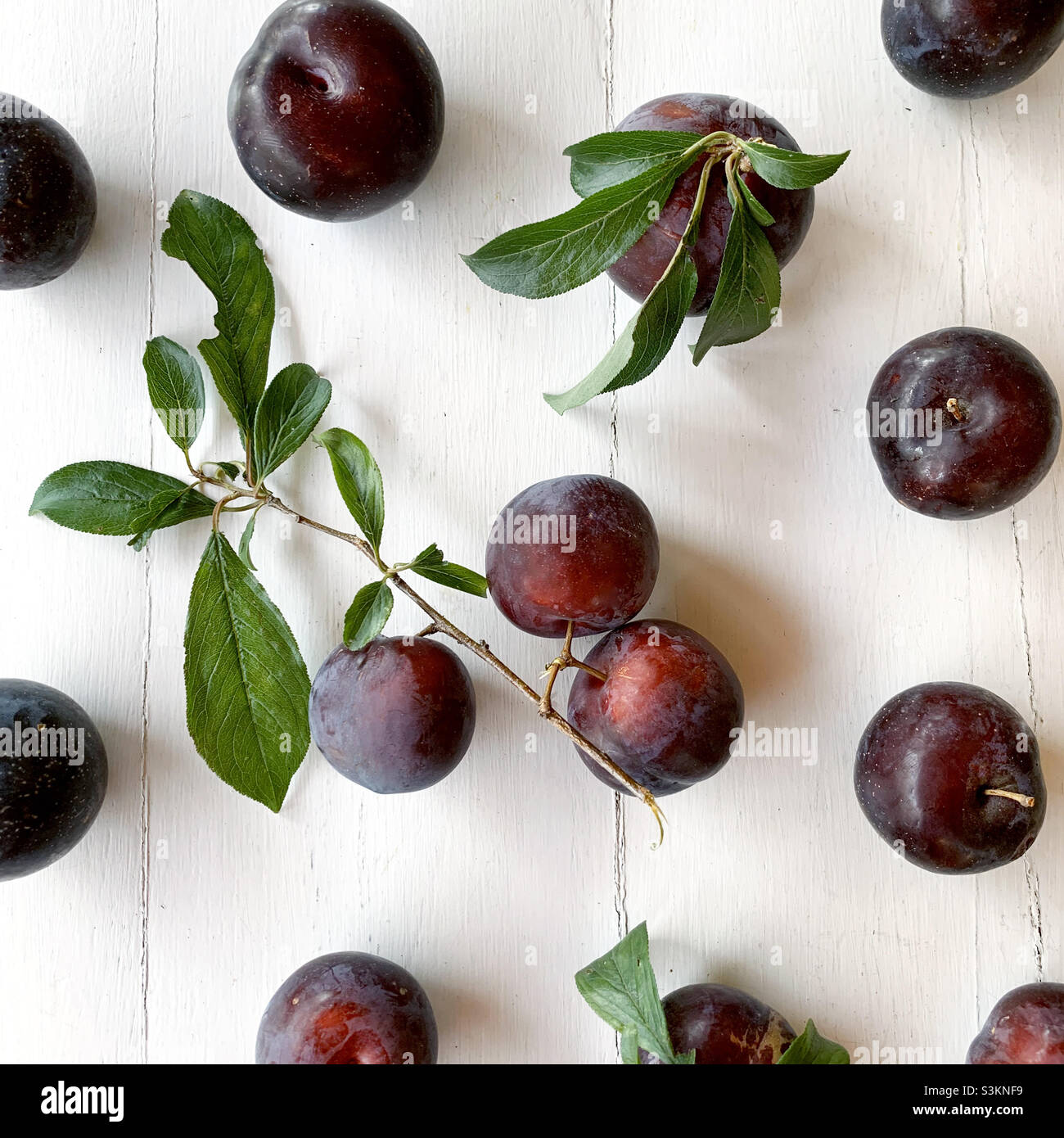 Red plums on white wood Stock Photo